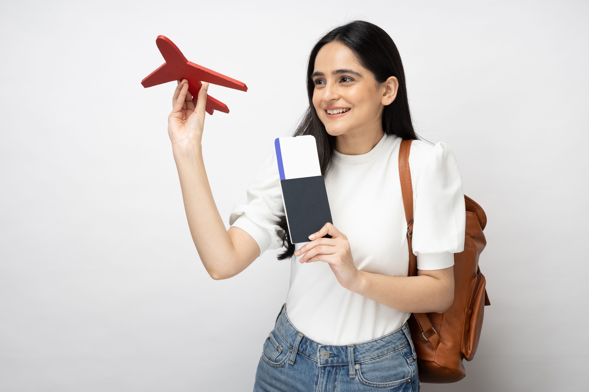 Portrait of young women student showing plane ticket and passport standing isolated over white background:- stock photo